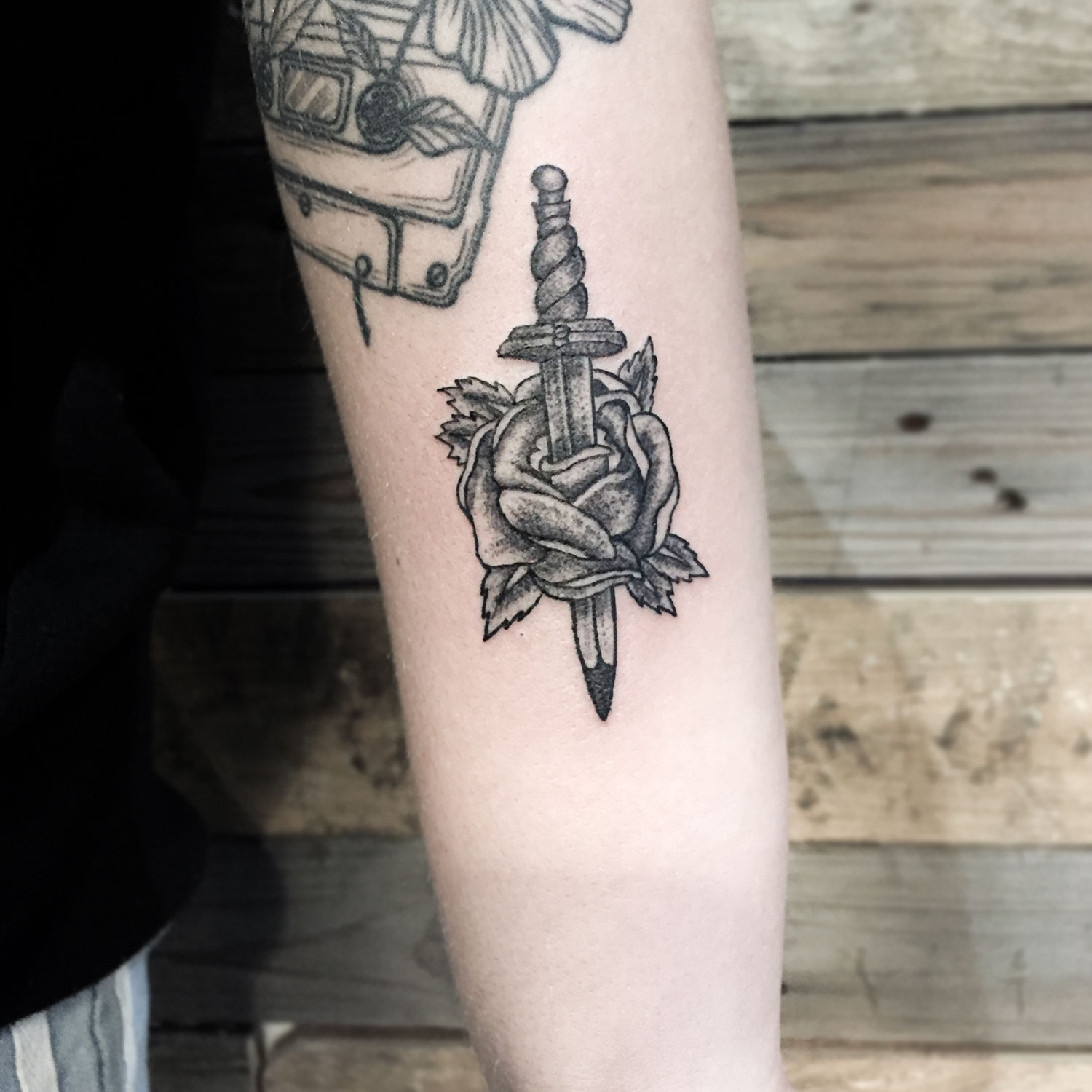 tatuaje blanco y negro de un corazón y una daga