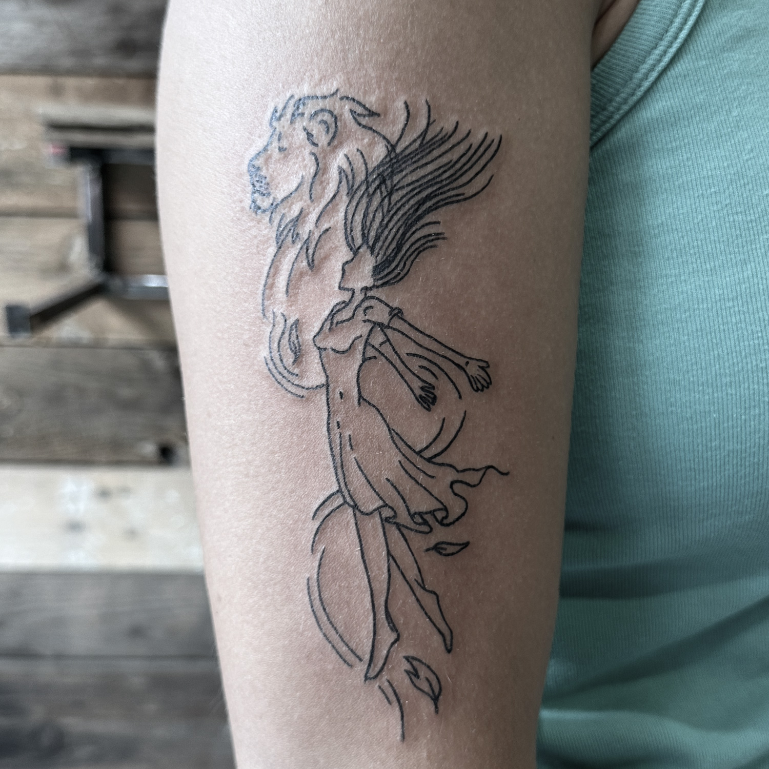 Tatuaje estilo fine line de una chica y un león