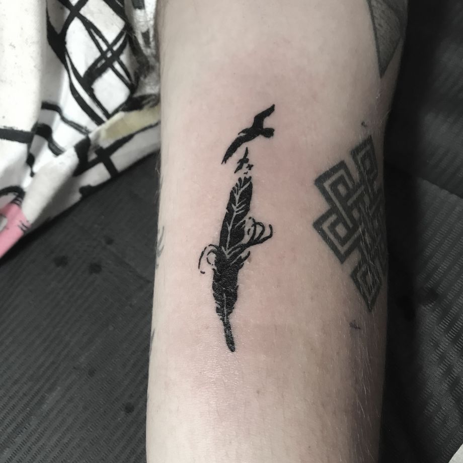 Tatuaje black work de una pluma y unos pájaros