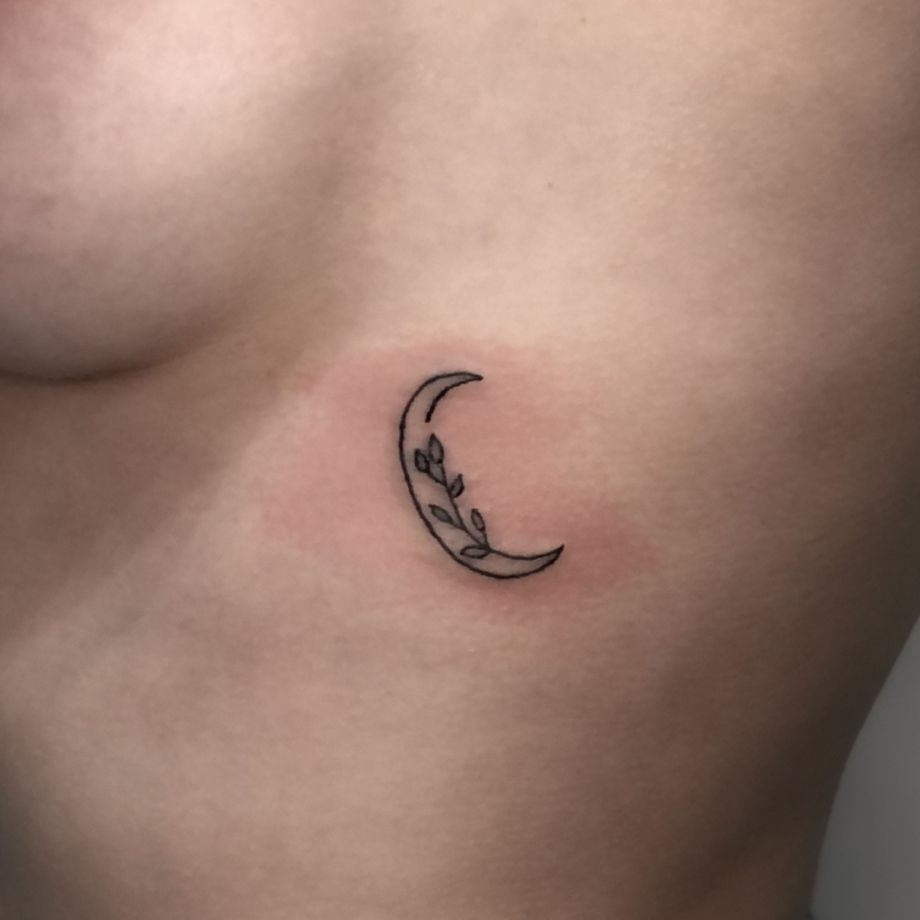 Tatuaje fine line de una luna y unas hojas