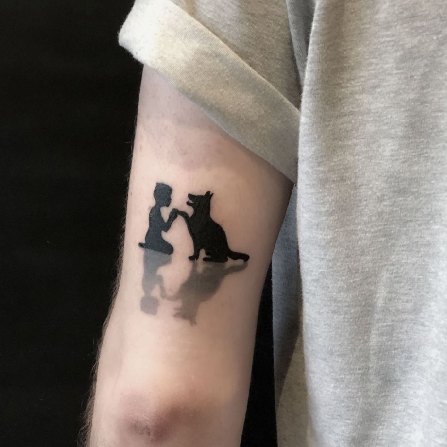 Tatuaje black work de un niño y un perro