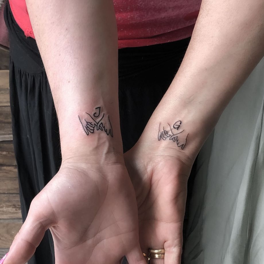 Tatuajes fine line de dos manos entrelazadas